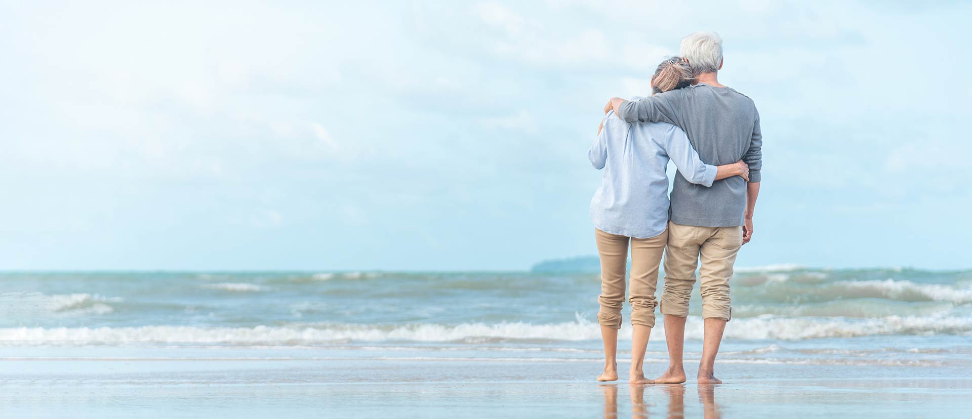 urovision-unbeschwert-leben-mit-inkontinenz Ein älteres Paar steht Arm-in-Arm am Strand und schaut aufs Meer